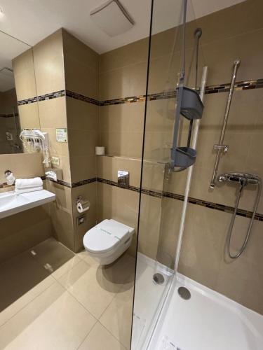 a bathroom with a shower and a toilet and a sink at Wellness Hotel Panorama in Trenčianske Teplice