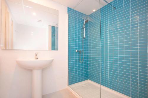 a bathroom with a sink and a shower with blue tiles at BLUESEA Arenal Tower Adults Only in El Arenal