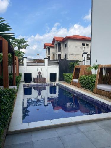 a swimming pool with two chairs and a house at Kemadjou Boutique Stay in Yaoundé