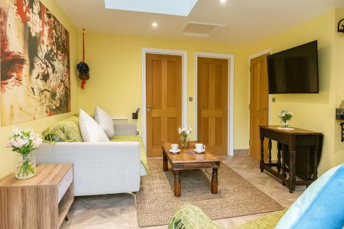 a living room with a white couch and a tv at Restful Break 2 BR Woods Cottage 2 Acre Garden gated free Parking in Chislehurst