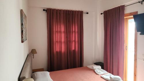 a bedroom with a bed and a window with red curtains at Dionysus House Lasithi Plateau in Magoulás