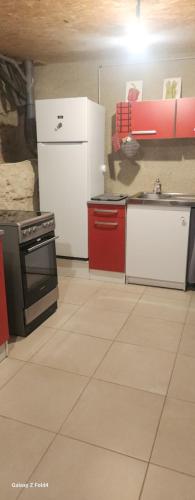 a kitchen with white appliances and red cabinets at Les Figuets in Châteauneuf-de-Galaure