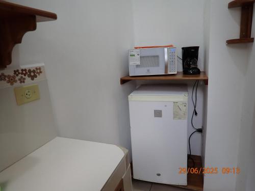 a small kitchen with a microwave on top of a refrigerator at The Finch House (La Casa del Pinzón) in Puerto Ayora