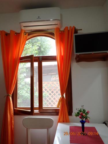 a room with a window with orange curtains and a table at The Finch House (La Casa del Pinzón) in Puerto Ayora