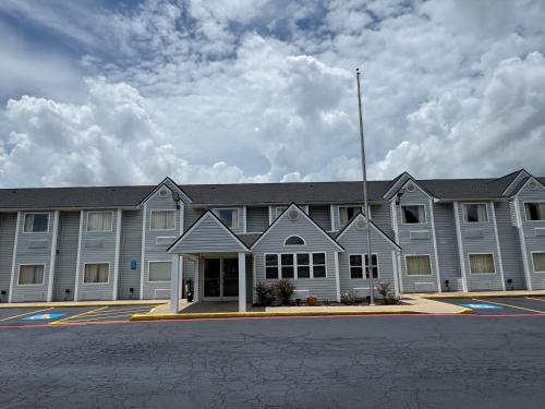 a large gray building with a parking lot at Americas Best Value Inn and Suites Ada in Ada