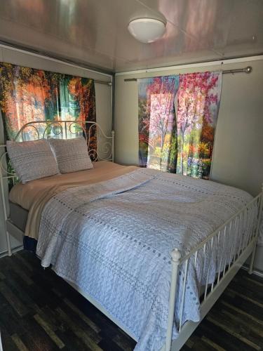 a bedroom with a white bed with two large windows at Farm house in Kelso