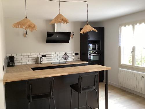 a kitchen with a counter and two stools at a bar at Maison de famille in Écommoy
