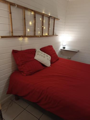 a bed with a red blanket and two red pillows at Chez RAM'S in Le Tampon