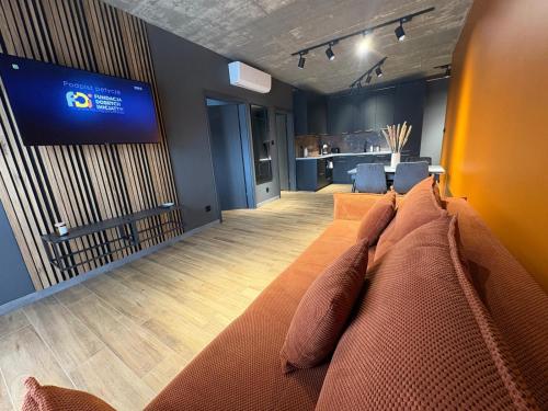 a living room with a large couch and a television at Apartament Baltic 13 Mielno in Mielno