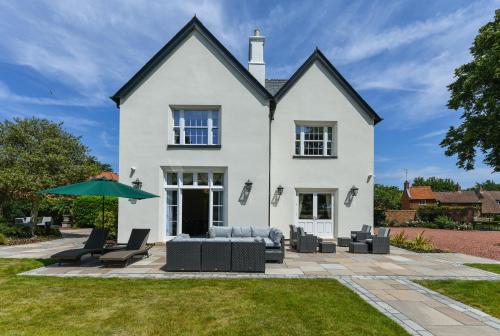 Casa blanca con sillas y sombrilla en Stunning Rectory in Countryside with Hot Tub, en Thurgarton