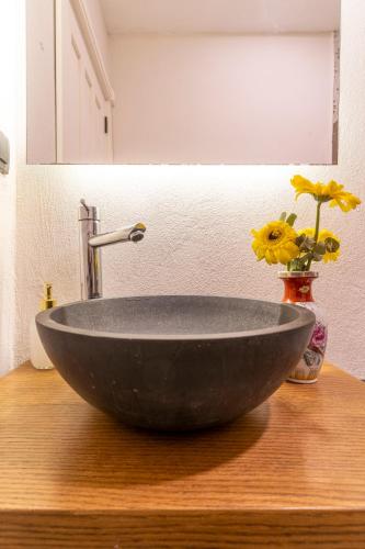 a black bowl sink on a wooden counter with a vase with flowers at Mediha Hanım Konağı Alaçatı in Cesme