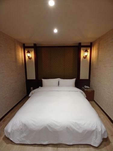 a large white bed in a room with two lights at 4F, Welcome International traveller, long stay in Busan