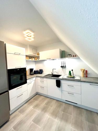a kitchen with white cabinets and appliances in an attic at Fewo II Graal-Müritz Sobierajczyk in Graal-Müritz