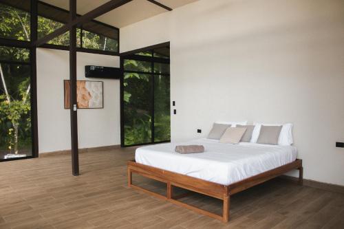 a bedroom with a bed with white sheets and windows at Maze Lodge in Puerto Jiménez