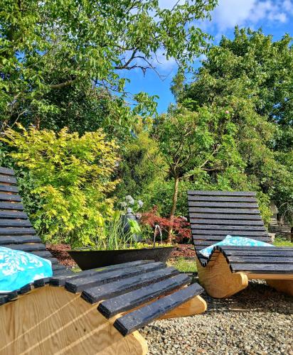 two wooden benches sitting in a garden with trees at Eleonor Accommodation in Liszki