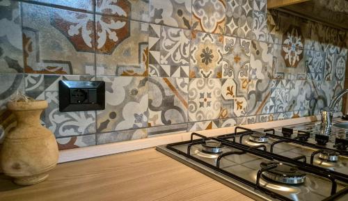 a kitchen with a stove and a tile wall at Paglia d'Oro Luxury Flat in Lotzorai