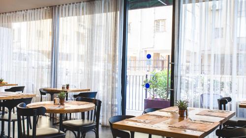 a restaurant with tables and chairs and large windows at Roxon Sea Sand Bat Yam in Bat Yam