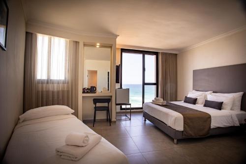 a hotel room with two beds and a desk at Roxon Sea Sand Bat Yam in Bat Yam
