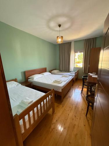 a room with two beds and a table and a desk at Meti guest house in Krujë