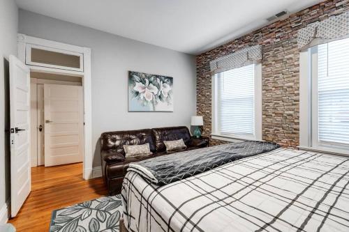 a bedroom with a large bed and a brick wall at Grand Carytown 5BR FAN HOME fully fenced in Richmond