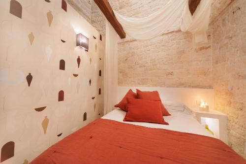 a bedroom with a red bed and a brick wall at AGLEA trulli e suite in Alberobello