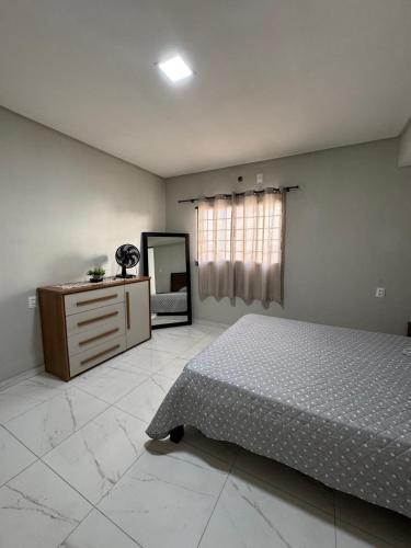 a bedroom with a bed and a dresser and a mirror at Casa aconchegante in Petrolina