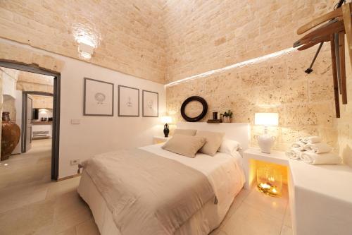 a bedroom with two beds and a brick wall at AGLEA trulli e suite in Alberobello