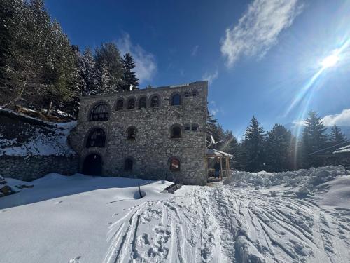 a building in the snow with footprints in the snow at Kulla Guest House in Peje