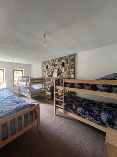 a bedroom with two bunk beds and a stone wall at Kulla Guest House in Peje