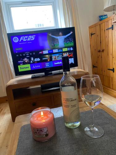 a candle and a bottle of wine and a glass at Llwyn Celyn 2 bedroom in Bala