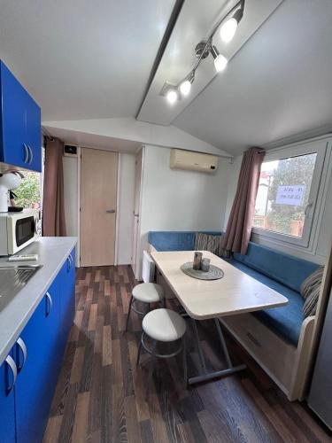 a caravan kitchen with a table and a blue couch at Bungalow COSTA BRAVA in L'Escala