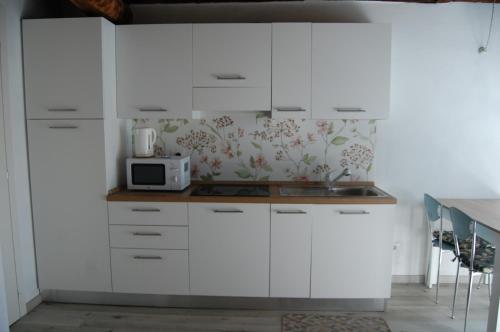 a kitchen with white cabinets and a microwave at PRIMA DEL CIELO - appartamento MONTI in Esino Lario