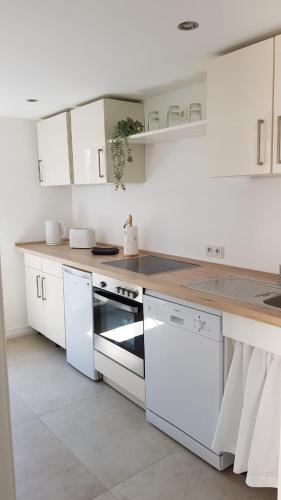 una cucina con armadietti bianchi ed elettrodomestici bianchi di ME Apartments - Erbach a Bad Camberg