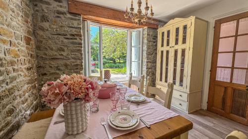 a dining room with a table with a vase of flowers at La Maison de Cécile in Cahan