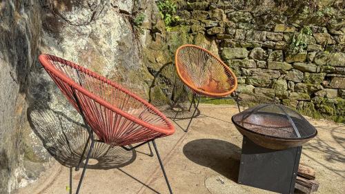 two chairs and a trash can next to a stone wall at La Maison de Cécile in Cahan