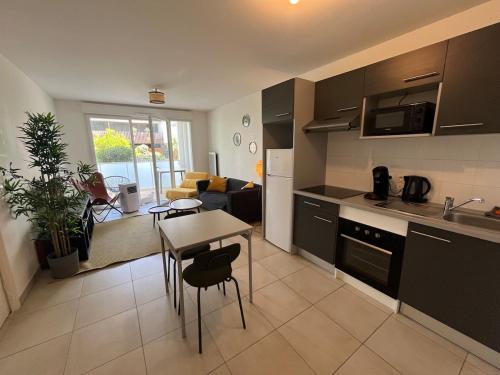 une cuisine et un salon avec une table et des chaises dans l'établissement Joli T2 Terrasse Parking privé Confort, à Montpellier