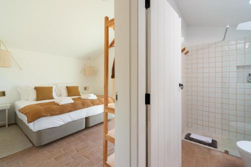 a bedroom with a bed and a bathroom with a shower at Monte das Casolas in Grândola