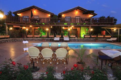 a resort with a table and chairs next to a pool at The Pearl of the Golan - Pnina BaGolan in Had Nes