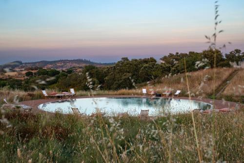 a small pool in a field with chairs in it at Monte das Casolas in Grândola
