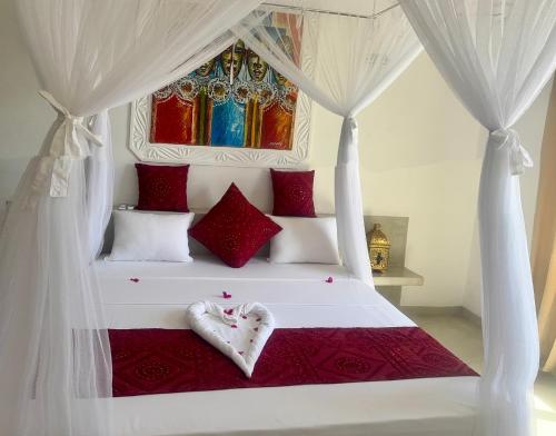 a bedroom with a white bed with red pillows at Luxury Penthouse 7 Islands View at Ocean Pearls in Watamu