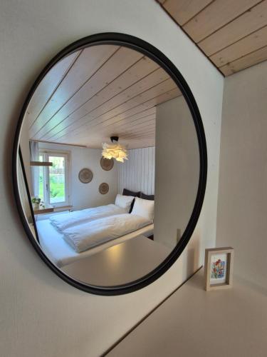 a round mirror in a bedroom with a bed at Villa Donkey Ferienwohnung in Degersheim