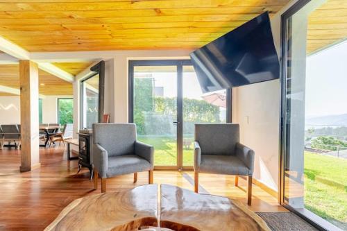 a living room with two chairs and a tv at LUXO Casa en Valle de Bravo con jacuzzi y espectacular vista al lago in Valle de Bravo