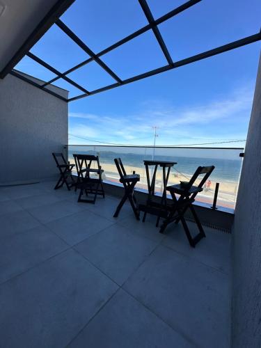 a patio with tables and chairs on the beach at Pousada orla Mar in Maricá