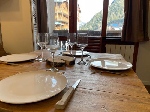 une table en bois avec des assiettes et des verres à vin dessus dans l'établissement Studio cosy aux pieds des pistes, à Valfréjus