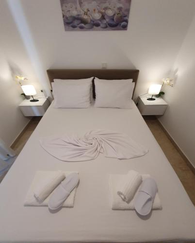 a large white bed with two towels and two lamps at Home sweet home in Loutraki