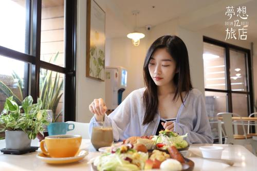a woman sitting at a table with a plate of food at Dream 12 Hotel in Taichung
