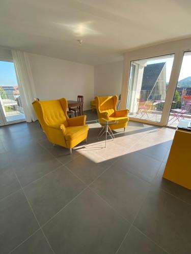 a living room with two yellow chairs and windows at Upper Floor in Oberburg