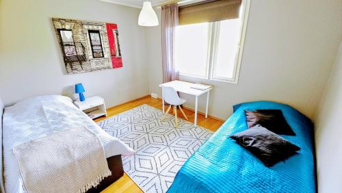 a bedroom with a blue bed and a desk at Wifi ja työpisteellä varustettu viihtyisä huone in Kerava