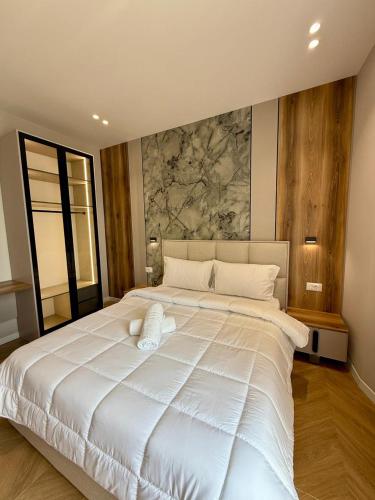 a large white bed in a bedroom with a painting on the wall at Gent's Inn Luxury in Durrës