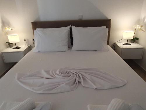 a white bed with a blanket on it with two lamps at Home sweet home in Loutraki